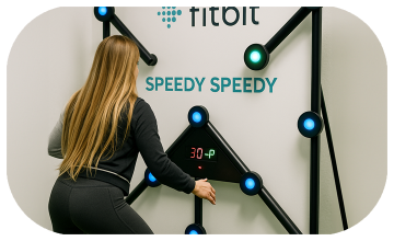 Woman playing Batak reaction game at a fitness event in Dubai, touching illuminated buttons to test her speed and reflexes. "Speedy Speedy" displayed on wall.